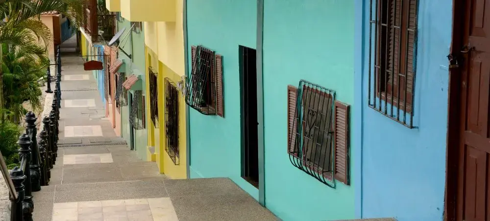 Colorful colonial houses with turquoise, yellow and blue facades line a cobblestone street in historic Guayaquil