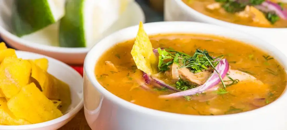 Traditional Ecuadorian encebollado soup with fresh fish, onions, and herbs served with crispy plantain chips