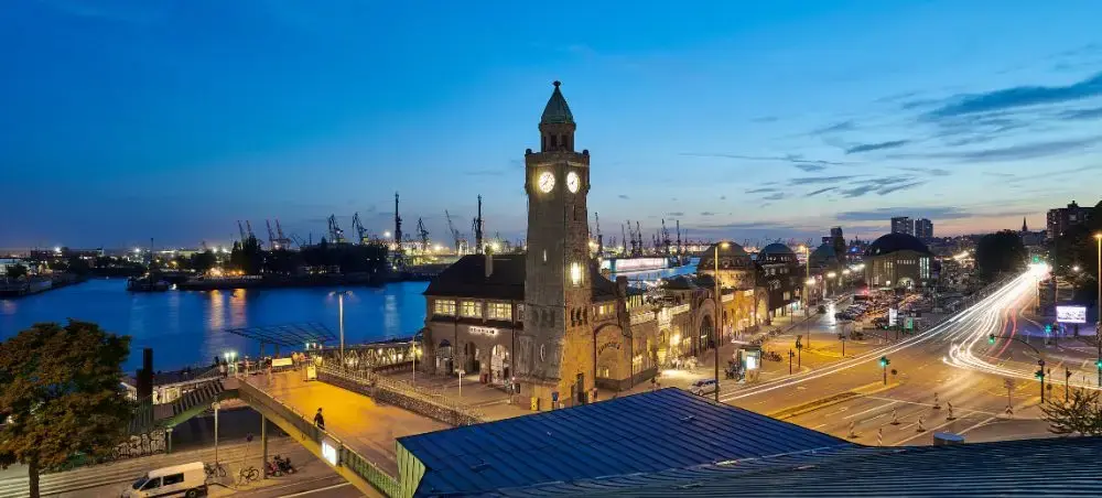 Hamburg's iconic clock tower and harbor illuminated at twilight with port cranes and traffic trails