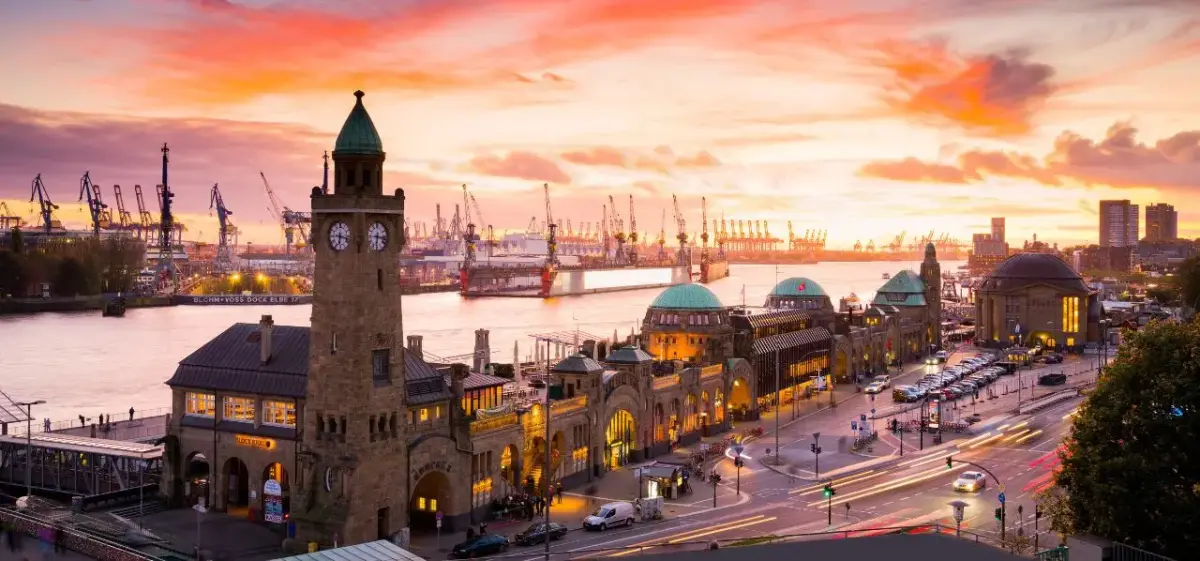 Hamburg's historic waterfront and port at sunset with illuminated Landungsbrücken pier and colorful sky