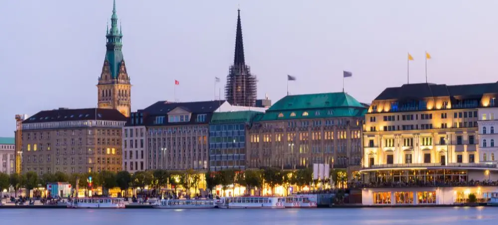 Hamburg waterfront at twilight showcasing historic architecture and illuminated buildings along the Alster lake