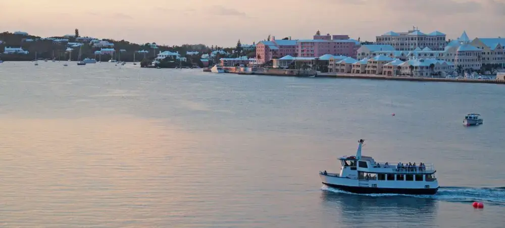 Hamilton harbor at sunset with passenger ferry and colorful waterfront buildings in Bermuda