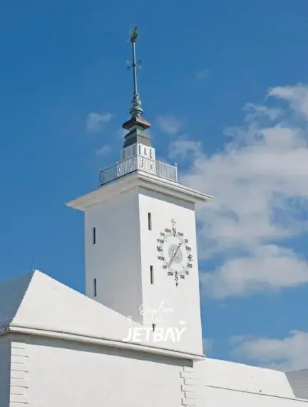 Historic white clock tower with ornate timepiece against blue sky in Hamilton, Bermuda's downtown district