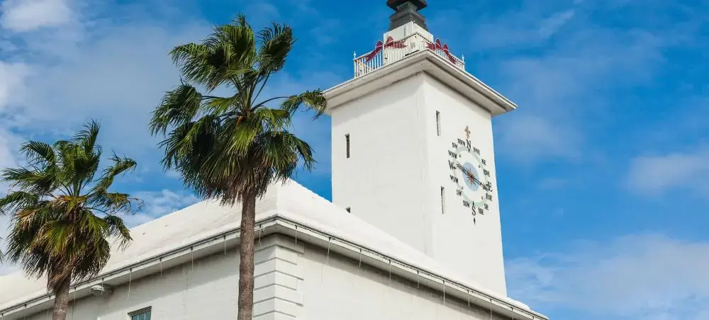 White colonial clock tower with palm trees against blue sky in Hamilton, Bermuda's historic center