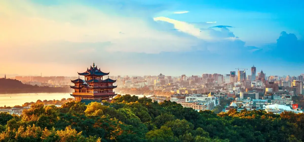 Hangzhou skyline at golden hour featuring traditional pagoda amid lush greenery and modern cityscape