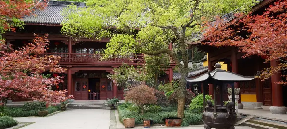 Traditional Chinese temple courtyard in Hangzhou with red maple trees and historic wooden architecture