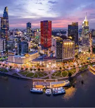 Ho Chi Minh City skyline at sunset with illuminated skyscrapers and Saigon River waterfront in Vietnam