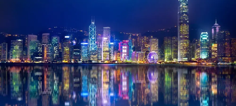 Hong Kong skyline at night with illuminated skyscrapers reflecting in Victoria Harbour waters