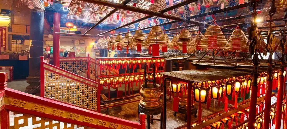 Traditional Hong Kong temple interior with red lanterns, incense coils, and ornate wooden architecture