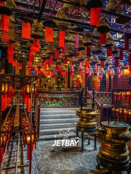 Traditional Hong Kong temple interior with red lanterns, incense coils, and ornate bronze vessels