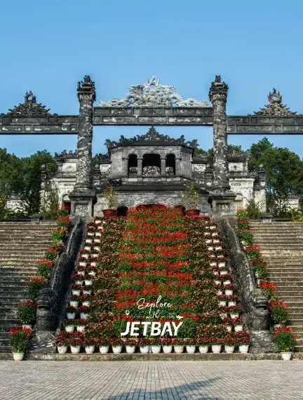 Ornate stone gateway and ceremonial stairs at Hue Imperial Citadel with colorful flower displays