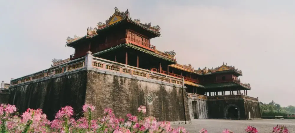 Historic Imperial City fortress in Hue with traditional Vietnamese architecture and blooming flowers