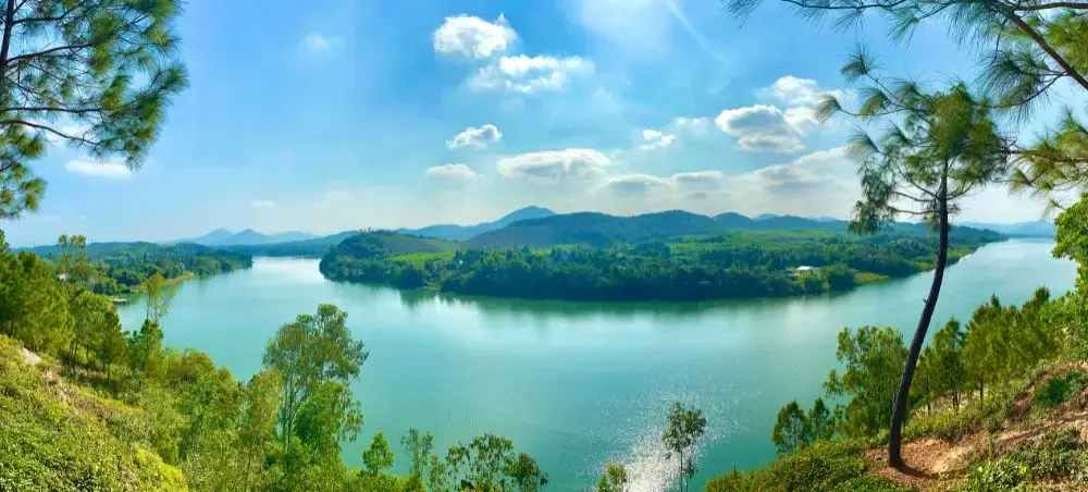 Panoramic view of Perfume River winding through lush green mountains and forests surrounding Hue, Vietnam