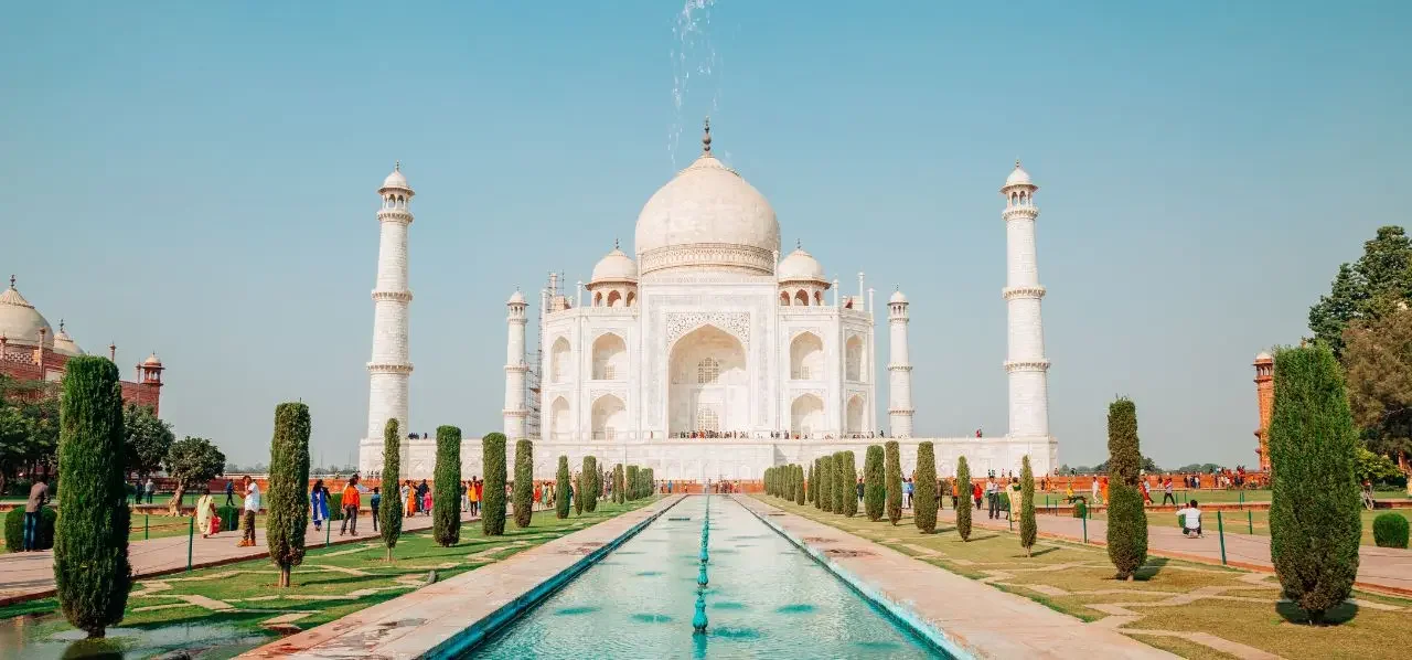 Taj Mahal's iconic white marble dome and minarets rising majestically above manicured gardens in Agra, India