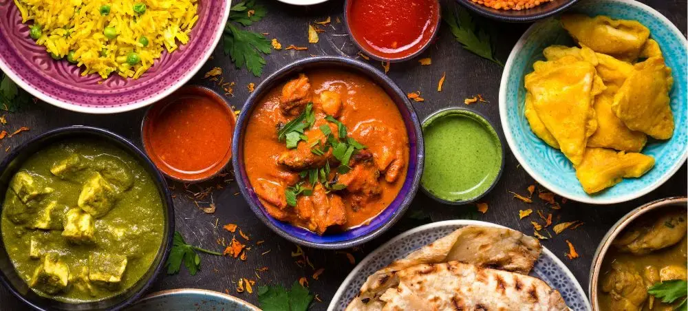 Authentic Indian cuisine spread featuring curry dishes, naan bread, and colorful spices for luxury travel dining
