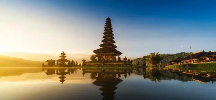 Iconic Balinese temple pagoda reflecting in serene lake waters at golden sunrise in Indonesia