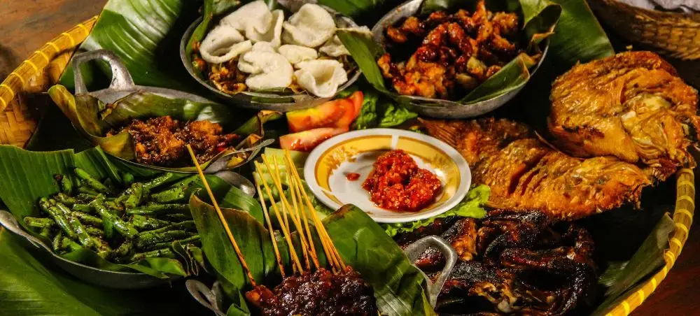 Traditional Indonesian feast with grilled satay, rendang, and spiced vegetables served on banana leaves