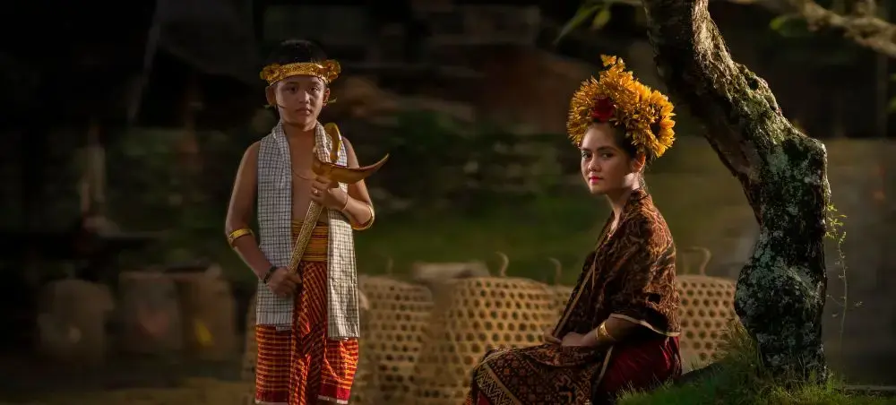 Traditional Indonesian performers in ornate ceremonial dress showcase cultural heritage beneath tropical trees
