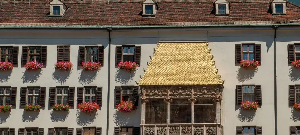 Historic Innsbruck building with golden roof balcony and flower-adorned windows showcasing Austrian alpine architecture