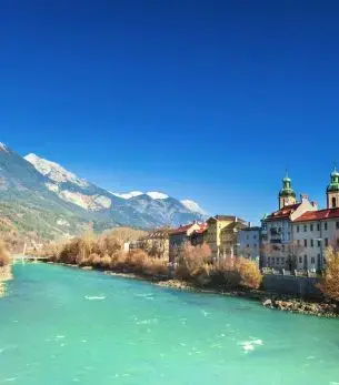 Turquoise Inn River flowing through historic Innsbruck with snow-capped Austrian Alps and baroque architecture