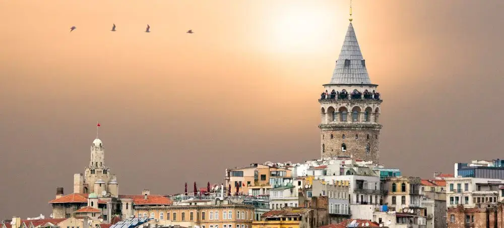 Galata Tower dominates Istanbul's historic skyline at sunset with traditional Ottoman architecture below