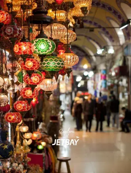 Colorful Turkish lanterns illuminate historic Grand Bazaar corridor in Istanbul with shoppers exploring