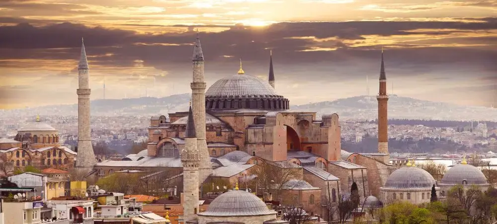 Hagia Sophia's iconic dome and minarets dominate Istanbul's historic skyline at golden hour sunset