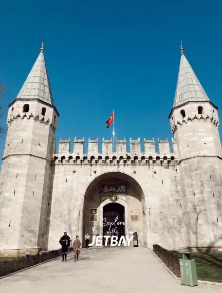 Historic Topkapi Palace entrance gate with twin towers and Turkish flag in Istanbul, Turkey