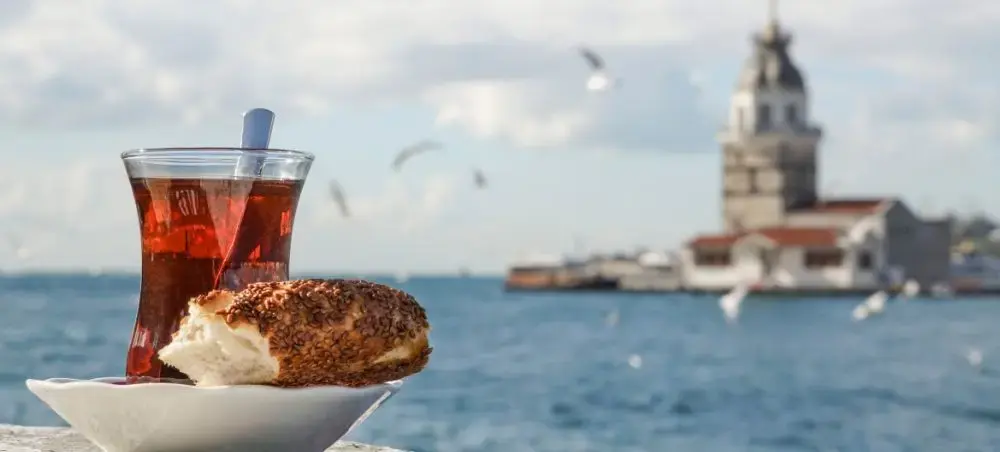 Traditional Turkish tea and simit pastry overlooking Istanbul's Maiden's Tower and Bosphorus waters