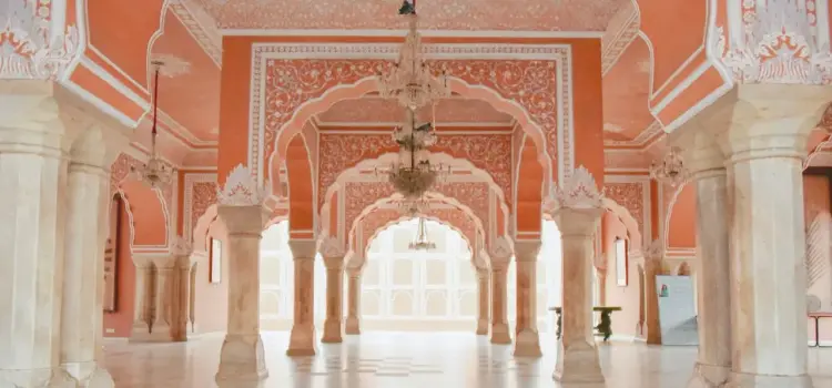 Ornate pink sandstone palace interior with carved arches and columns showcasing Jaipur's royal architecture