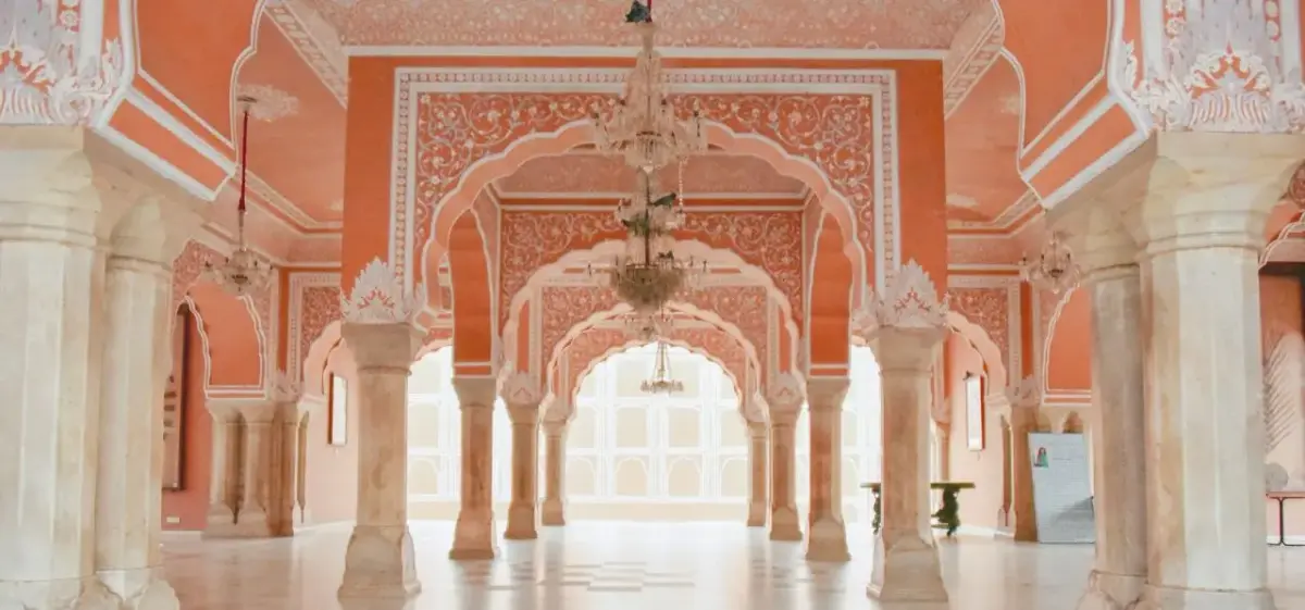 Ornate pink sandstone palace interior with carved arches and columns showcasing Jaipur's royal architecture