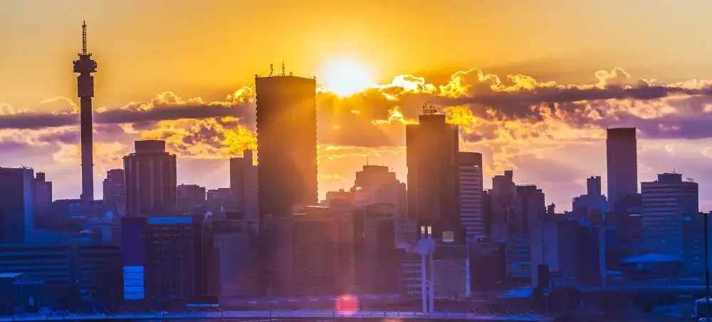 Johannesburg skyline at golden hour with dramatic sunset clouds illuminating the city's modern towers
