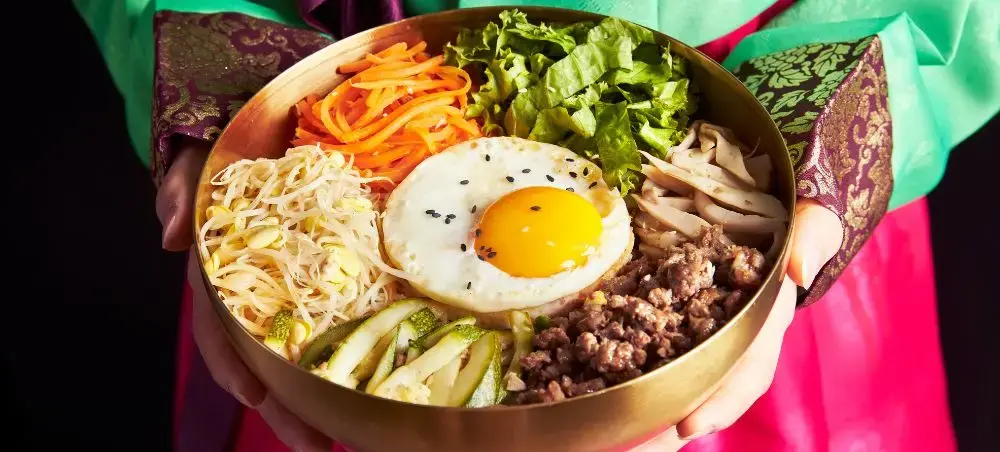 Traditional Korean bibimbap bowl with rice, vegetables, fried egg and meat served during luxury travel