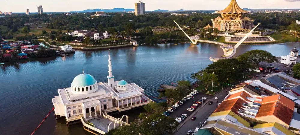 Aerial view of Kota Kinabalu waterfront featuring floating mosque and State Assembly building along Likas Bay