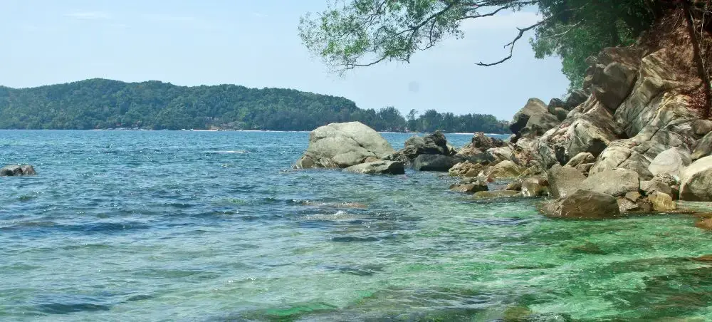 Crystal clear turquoise waters and granite boulders along Kota Kinabalu's pristine coastline in Malaysia