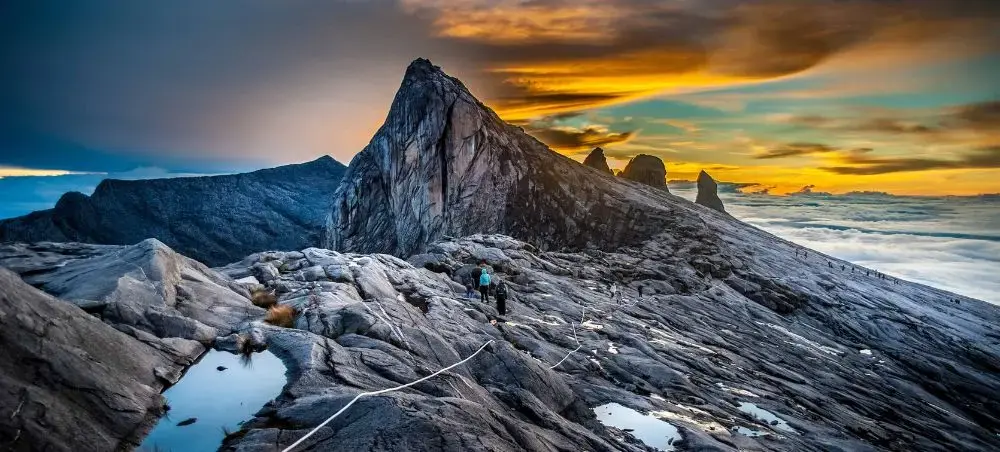 Climbers ascending Mount Kinabalu's rocky summit at sunrise in Kota Kinabalu, Malaysia's premier destination