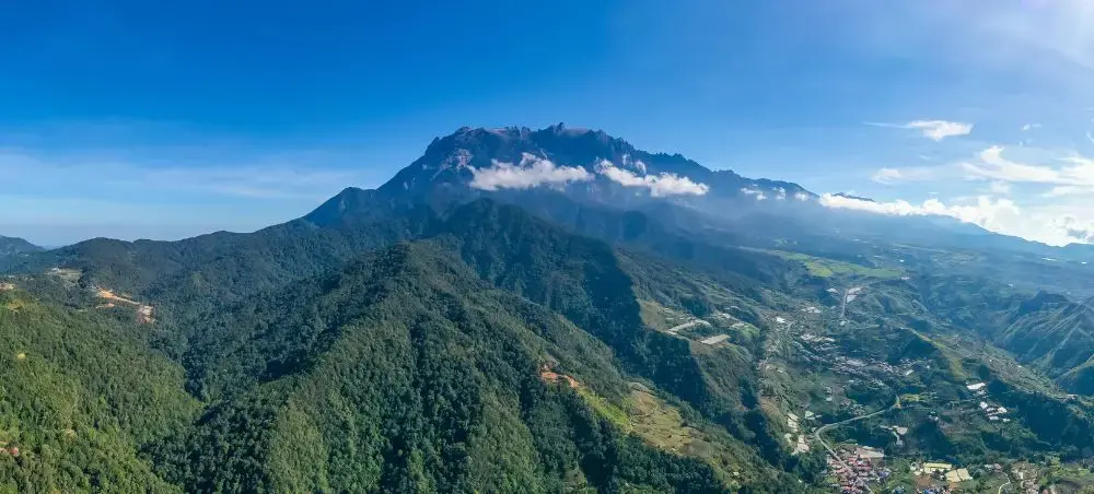 Mount Kinabalu towering over lush green valleys and settlements in Kota Kinabalu, Malaysia