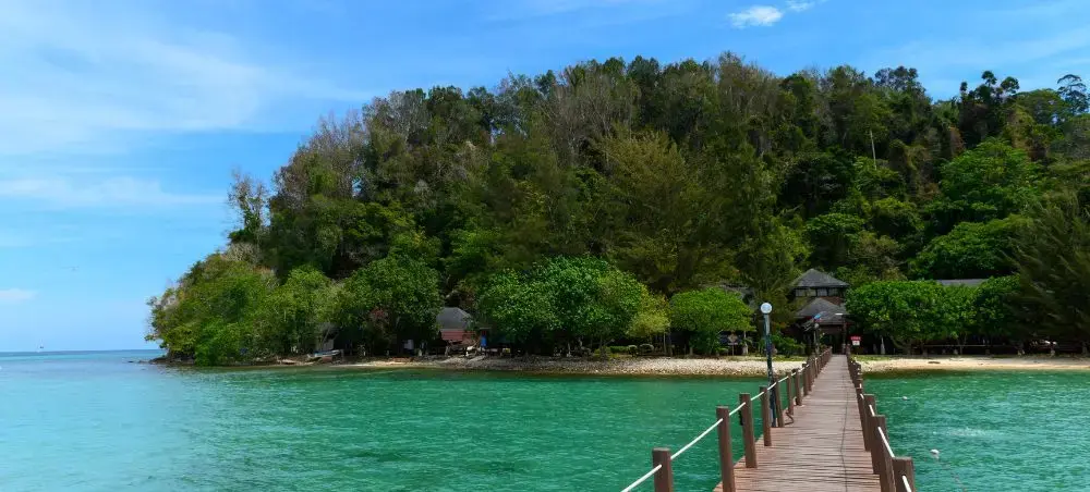 Wooden jetty extending over turquoise waters to tropical island resort near Kota Kinabalu, Malaysia