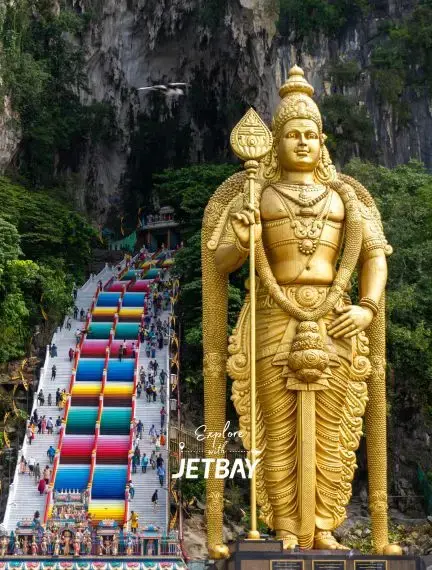 Golden Lord Murugan statue towering over colorful Batu Caves steps in Kuala Lumpur Malaysia