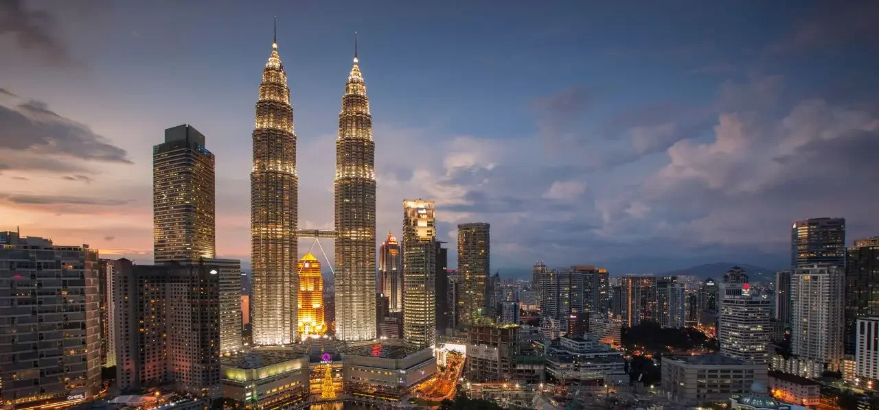 Illuminated Petronas Twin Towers dominating Kuala Lumpur's glittering skyline at dusk in Malaysia