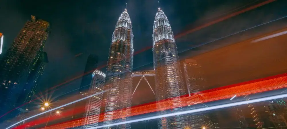 Petronas Twin Towers illuminated at night with light trails from traffic in Kuala Lumpur Malaysia