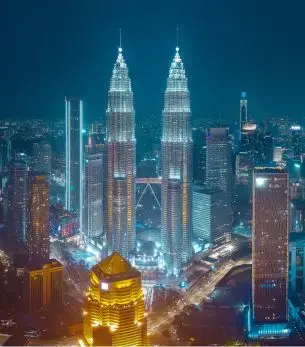 Illuminated Petronas Twin Towers dominating Kuala Lumpur's glittering skyline at night in Malaysia