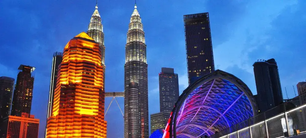 Kuala Lumpur skyline at dusk featuring illuminated Petronas Twin Towers and modern skyscrapers in Malaysia