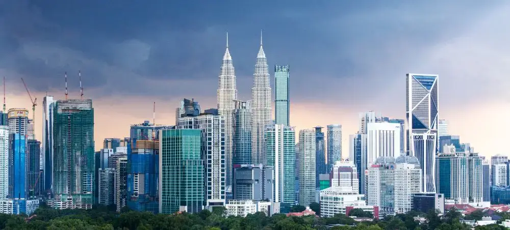 Kuala Lumpur skyline featuring iconic Petronas Twin Towers and modern skyscrapers at sunset