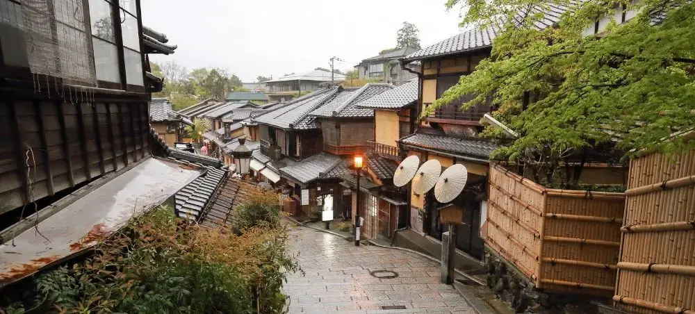 Traditional wooden buildings and stone pathways in historic Kyoto district showcase authentic Japanese architecture