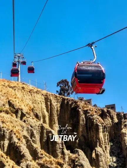 Red cable car gondolas soar above dramatic rocky cliffs in La Paz, Bolivia's unique urban transportation system