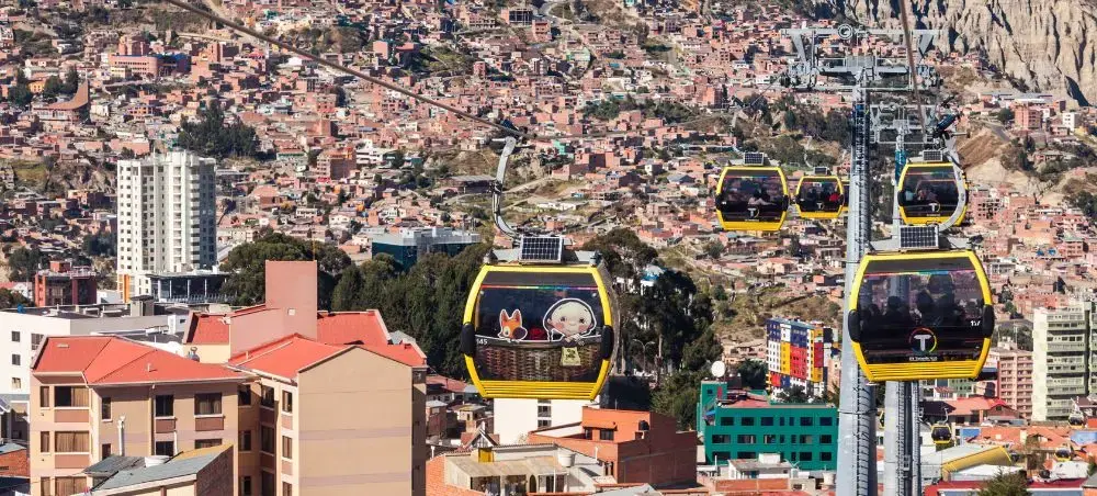Yellow cable car gondolas transport passengers above La Paz's sprawling hillside neighborhoods and buildings