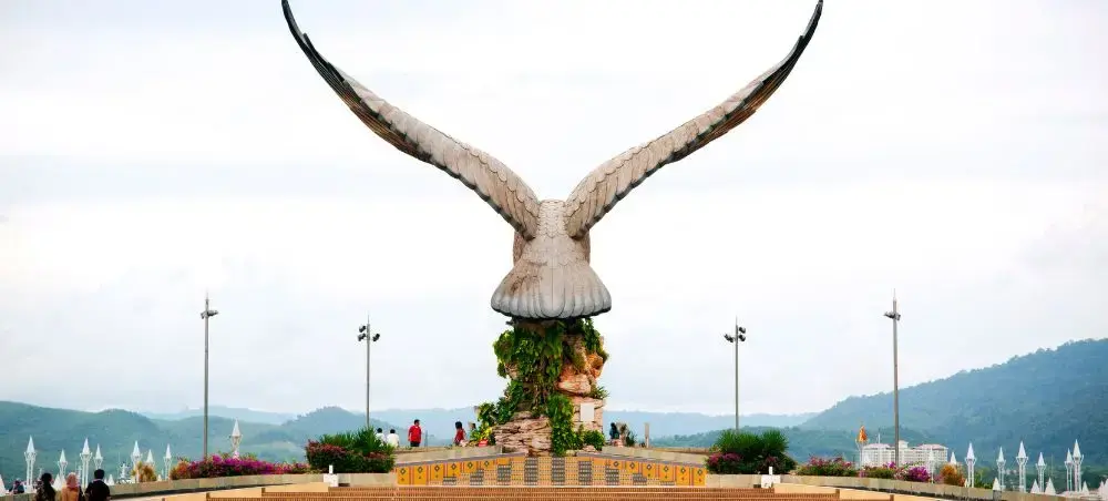Iconic Eagle Square monument in Langkawi showcasing the island's symbol against tropical mountains and harbor