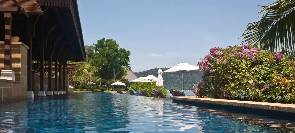 Luxury resort infinity pool overlooking tropical Langkawi landscape with palm trees and mountain views