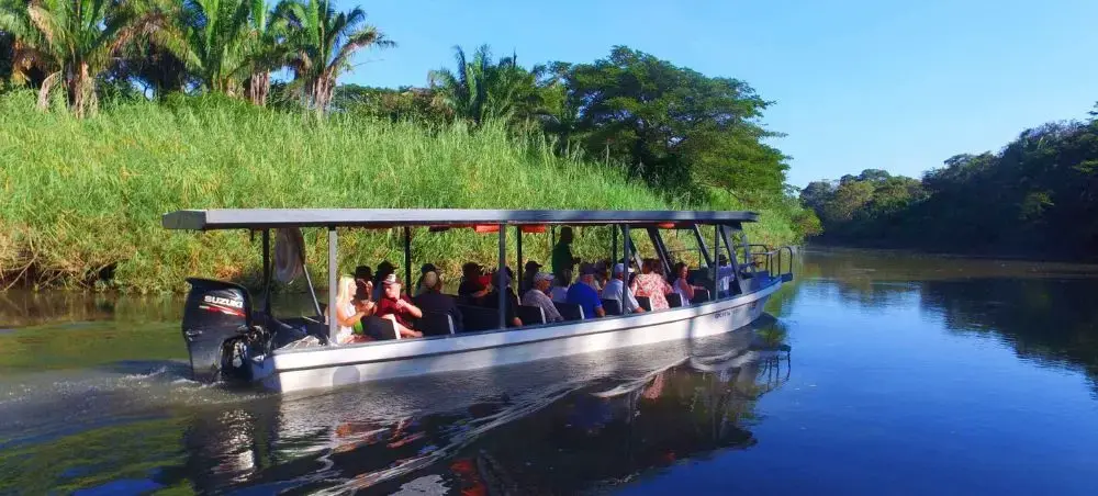 Tourist boat navigating tropical river surrounded by lush Costa Rican rainforest near Liberia